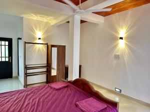 a bedroom with a purple bed and a ceiling at FAM Hotel in Unawatuna