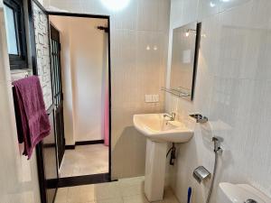 a white bathroom with a sink and a mirror at FAM Hotel in Unawatuna