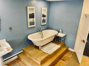 a bathroom with a white tub and a blue wall at Griffin Inn in Irnham +9 photos