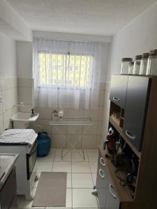 una piccola cucina con un lavandino e una finestra di Aparatamento mobiliado residencial Sol e Mar a Ilhéus