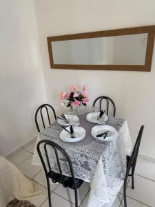 un tavolo con due sedie e un vaso con fiori rosa di Aparatamento mobiliado residencial Sol e Mar a Ilhéus 1 altra foto
