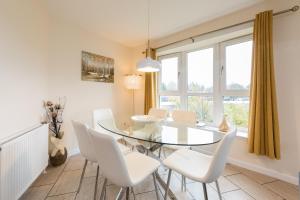ein Esszimmer mit einem Glastisch und weißen Stühlen in der Unterkunft Monart Stylish City Centre Apartment, 2 Bed, sleeps 6 in Perth