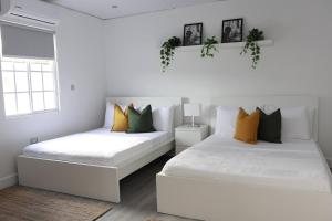 deux lits dans une chambre avec des oreillers blancs et jaunes dans l'établissement Eshae Living - Cosy 2BR with breakfast & pool, à Stanmore Grove 27 autres photos
