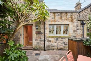 an old stone house with a red door at Host & Stay - Sonsy Cottage in Alnmouth