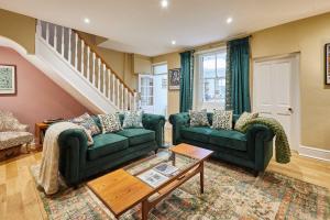 a living room with two green couches and a table at Host & Stay - Sonsy Cottage in Alnmouth +12 photos