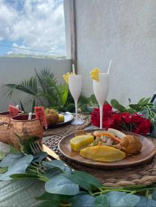 une table avec une assiette de nourriture et deux verres à vin dans l'établissement Eshae Living - Spacious 2BR with breakfast & pool, à Stanmore Grove