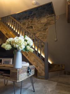 a vase of flowers on a table next to a staircase at Pink Cottage in Kirkcowan