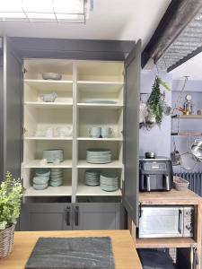 a kitchen with a cabinet filled with dishes at Pink Cottage in Kirkcowan