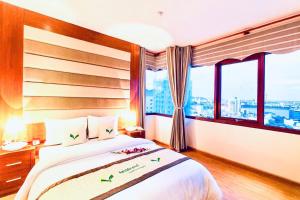 a bedroom with a large bed with a large window at MOONLIGHT Hotel & Suites - High floor, River view, Dragon Bridge view, City view in Da Nang