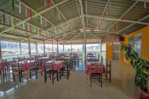Un comedor con mesas y sillas y ventanas. en VILLA andina cusco, en Cusco