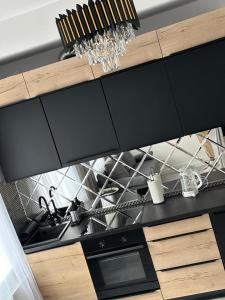 a kitchen with black cabinets and a sink at Royal Apartament in Gniezno