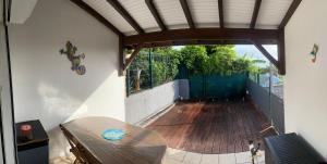 un patio con suelo de madera y mesa de madera en Turquoise Caraibes, en Chambort