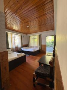 a bedroom with two beds and a wooden ceiling at NOLINA BOUTIQUE HOMESTAY in Namchi
