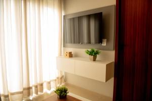 Zimmer mit einem TV und einem Fenster mit Pflanzen in der Unterkunft Apto Vista Mar 2 Suítes Piscina Japaratinga in São Bento + 36 Fotos