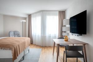 a bedroom with a bed and a desk and a television at PopUp - Stay3 self check in Apartments in Zürich
