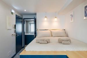 een slaapkamer met een groot wit bed met twee kussens bij Ponto Alto Hotel in Lissabon