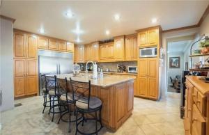 a kitchen with wooden cabinets and a island with bar stools at Three Bedroom Home with Guest Suite in San Pedro Peninsula Hospital Heliport