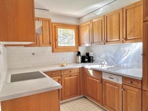 a kitchen with wooden cabinets and a sink at Chesa Foulla Rosa - 6 pax in Celerina