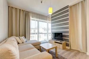 sala de estar con sofá y TV en Dom & House - Apartments Baltiq Plaza, en Gdynia