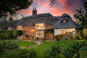 ein Reetdachhaus mit einem Sonnenuntergang im Hintergrund in der Unterkunft Castle Hill Cottage on a Scheduled Monument in Kenilworth