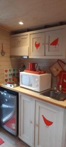 eine Küche mit einer Mikrowelle mit roten Vögeln darauf in der Unterkunft Rhododendron - La Roulotte Cocoon in Gèdre