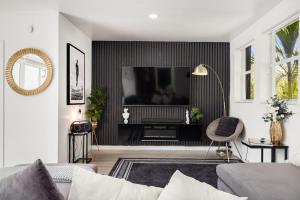 Una sala de estar con un sofá y un televisor. en Pura Vida Villa Miami Luxury Stay Pool & Hot Tub, en North Miami