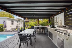 una cocina al aire libre con mesa y sillas junto a una piscina en Pura Vida Villa Miami Luxury Stay Pool & Hot Tub, en North Miami