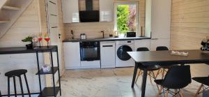 una cocina con electrodomésticos blancos, mesa y sillas en Sunny Baltic, en Jarosławiec