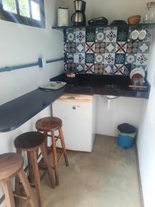 a small kitchen with two stools and a counter at Suíte com Cozinha Compacta in Guarapari