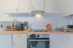 a kitchen with white cabinets and a wooden counter top at L'Escapade - Port Murano in Le Barcarès +18 photos