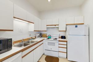 a white kitchen with a sink and a refrigerator at Beach Loop Condo #1 - North Unit in Bandon