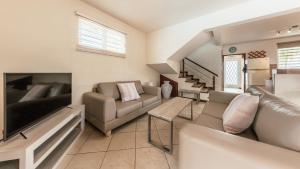 a living room with a couch and a tv and a couch at Villa Bayswater in Tamarin