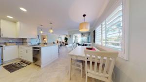 Una cocina con gabinetes blancos y una mesa y sillas. en Sanibel Surfside 226, en James Cipriani Heliport