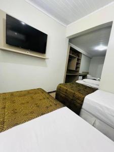 a hotel room with two beds and a flat screen tv at Hotel Zata - Econômico in Criciúma