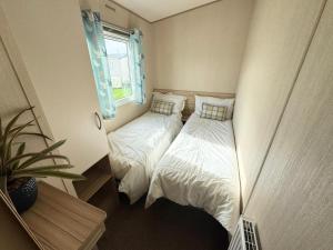 zwei Einzelbetten in einem kleinen Zimmer mit Fenster in der Unterkunft Park Dean Resorts Premium plot with Mountain view & Decking in Abergele
