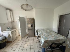 eine Küche mit einem Tisch und einem Kühlschrank in der Unterkunft Chambres individuelles dans maison familiale in Vierzon