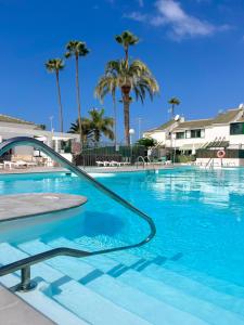 ein Swimmingpool mit einem Schlauch im Wasser mit Palmen in der Unterkunft Luxury bungalow Maspalomas Gran Canaria in Maspalomas
