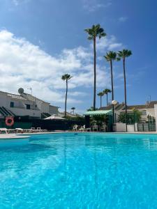 ein großer blauer Pool mit Palmen im Hintergrund in der Unterkunft Luxury bungalow Maspalomas Gran Canaria in Maspalomas + 25 Fotos
