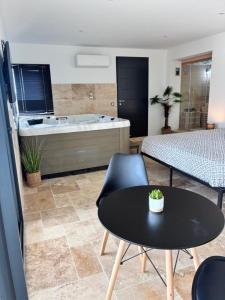 a living room with a table and a bath tub at Suite Privative Jacuzzi Sauna de la Villa Del Castagnol in Saint-Nexans