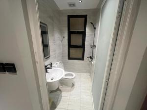 a white bathroom with a toilet and a sink at Quiet and comfortable apartment near Rakka Sea in Dammam