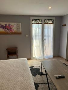 a living room with a table and two windows at chez Riva et Christophe in Luynes