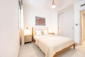 ein weißes Schlafzimmer mit einem Bett und einem Gemälde an der Wand in der Unterkunft Hydra 103 Poolview Luxury Apt Dominicus in La Laguna + 28 Fotos