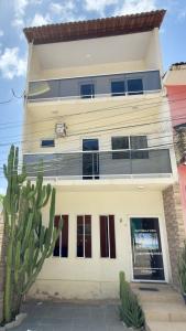 a white house with a cactus in front of it at Flat Bela Vista in Japaratinga