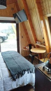 a bedroom with a bed and a table in a room at Tiny Home El descanso del Pescador in Puerto Cisnes