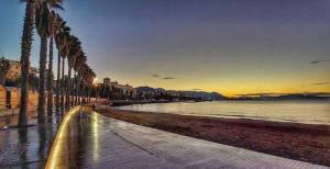 Una playa con palmeras y el océano al atardecer en Relais Luxury Retreat - Seafront Apartments, en Salerno