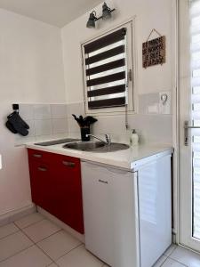 a kitchen with a sink and red cabinets and a window at Superbe studio de standing à 800m de la mer des Caraïbes le hameau de beauregard sainte anne in Sainte-Anne