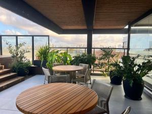 a patio with a wooden table and chairs and plants at Luxuoso Flat pé na areia no Restinga in João Pessoa