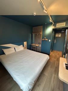 a large white bed in a room with a blue wall at Ibis Budget Lyon Caluire Cité Internationale in Caluire-et-Cuire