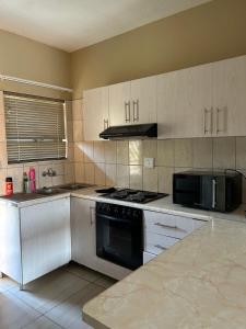 a kitchen with a stove and a microwave at MicasaKollections - Villa Ndahafa in Ongwediva