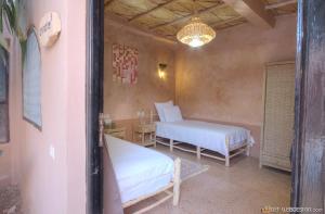 1 dormitorio con 2 camas, mesa y lámpara de araña en Guest House Bagdad Café, en Aït Ben Haddou 53 fotos más